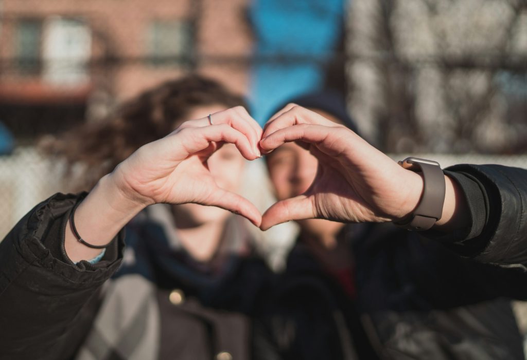 A girl holds up her hands to make the shape of a heart.