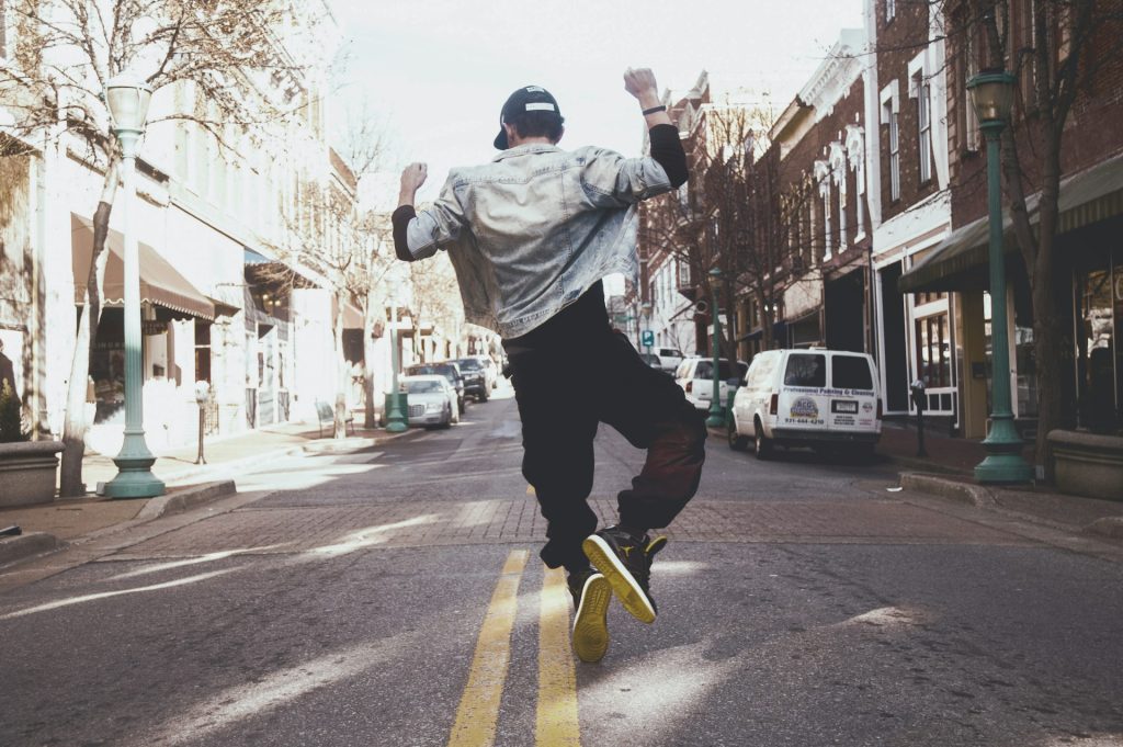 A man jumps in the street with his fists raised high, exhibiting joy.