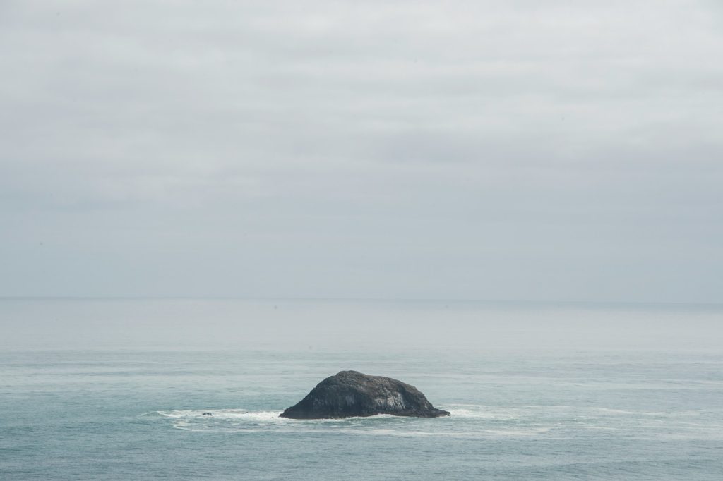 A single rock island juts out from the sea.