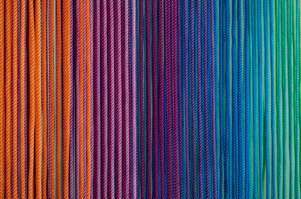 Should we use inclusive versions of the Bible? Vertical cords or stripes in a range of colours from oranges to pinks to blues to greens — representing diversity.