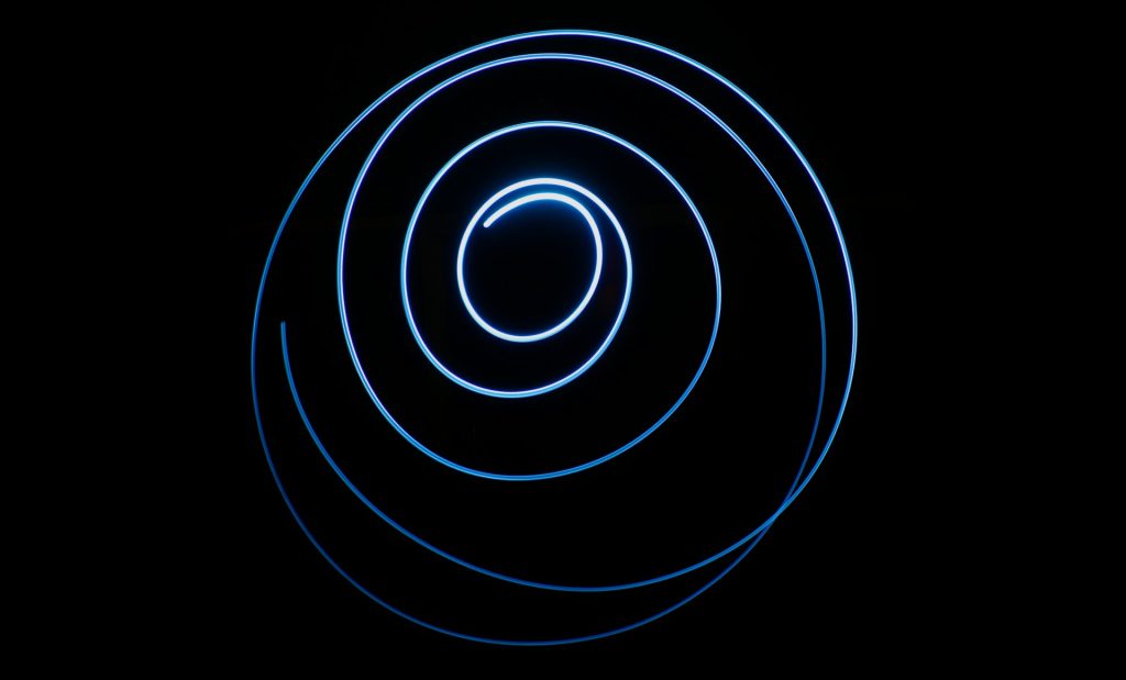 A blue ray of light traces an orbit against a black background.