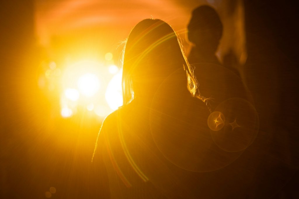 A person stands silhouetted against a bright light.